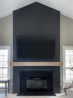 a living room with a fireplace and television mounted on the wall above it's mantle