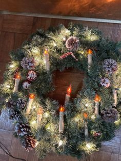 a wreath with lit candles and pine cones