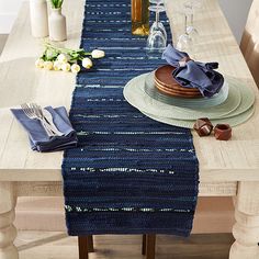 the table is set with plates, silverware and blue napkins on top of it