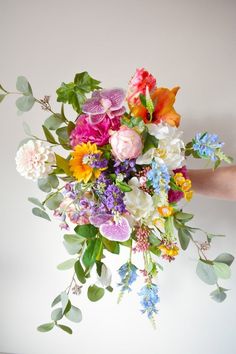 a bouquet of flowers is being held by someone's hand on a white background