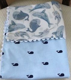 a blue and white baby blanket with whale print on the bottom, sitting on top of a wooden chair