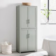 a bathroom with a white bath tub and two tall gray cabinets next to a window