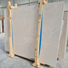 two large marble slabs in a warehouse with blue tape on the sides and one larger stone slab behind them