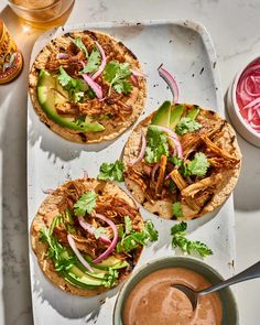 three pulled pork tacos with avocado, onions and cilantro sauce