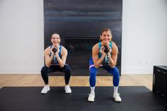 two women are doing squats in front of a fireplace