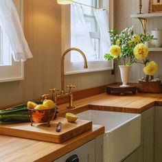 a kitchen with yellow flowers in a vase on the counter top next to a sink