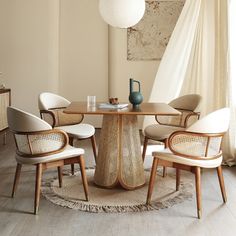 a dining room table with chairs and a vase on top of it in front of a window