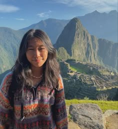 a woman standing on top of a mountain with mountains in the background