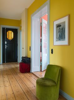 a green chair sitting on top of a hard wood floor next to a black door