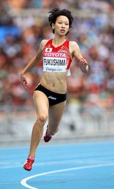 a woman running on a track in front of an audience