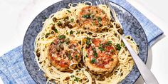 two pieces of meat with pasta on a blue and white plate next to a fork