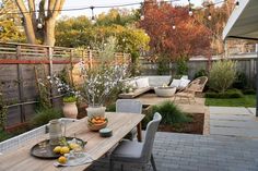 an outdoor dining area with wooden table, chairs and potted plants on the patio