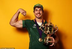 a man posing with a trophy and flexing his muscles