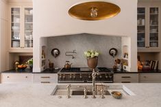 a kitchen with marble counter tops and gold accents on the hood over the stove top