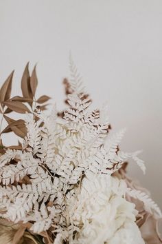 a bouquet of white flowers and greenery in a vase