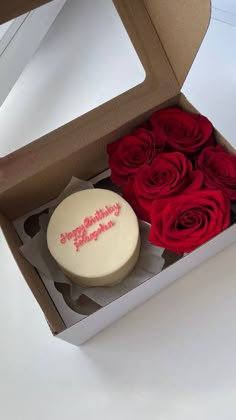 a white cake with red roses in a box