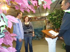 two men and a woman are standing in front of a table with papers on it