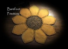 a close up of a flower made out of felt on a wooden table with the words barefoot primitives written below it