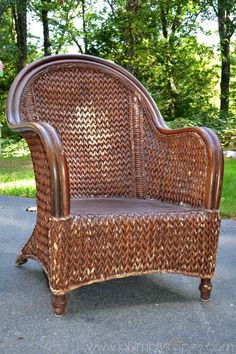 a wicker chair sitting on top of a cement ground next to some grass and trees