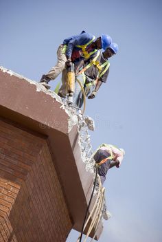 two men working on the side of a brick building stock photos - image 399782