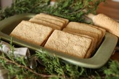 some cookies are sitting in a green tray on a table next to greenery and a rolling pin