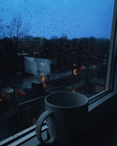 a coffee cup sitting on top of a window sill next to a rainy window