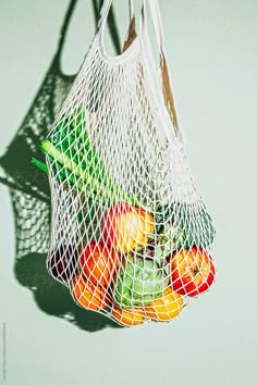 a white bag filled with lots of fruit sitting on top of a green table next to a wall