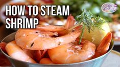 a metal bowl filled with shrimp next to a lemon wedge and garnished with herbs