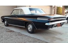 an old black car parked in front of a garage