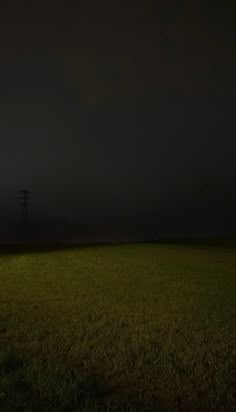 an empty field at night with power lines in the distance