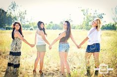 four young women holding hands in a field