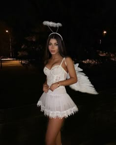 a woman in a white dress with angel wings on her head and one arm around her waist