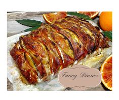 a large piece of meat sitting on top of a white plate next to oranges