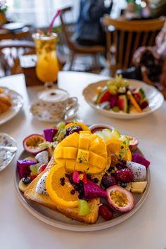 a white table topped with plates filled with fruit and veggies on top of it