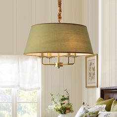 a lamp hanging from the ceiling in a bedroom next to a bed with pillows on it