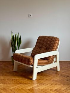 a chair sitting on top of a hard wood floor next to a potted plant