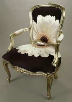 a chair with a flower painted on it's back and arms, sitting in front of a gray background