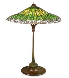 a stained glass lamp on a stand with a green base and gold trimmings