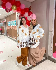 two women standing next to each other in front of balloons and teddy bears on the wall