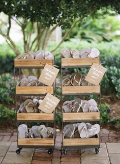 two wooden crates filled with shoes on top of a brick floor next to a tree