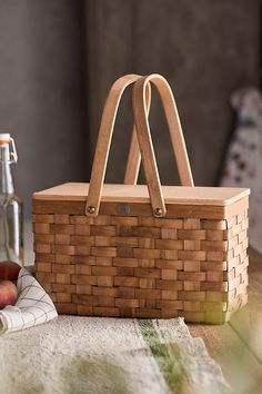 a wooden basket sitting on top of a table next to an apple and glass bottle