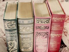 four books sitting on top of a bed in front of a comforter and pillows