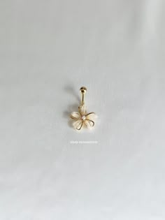 a gold nose ring with a flower on the front and back of it, sitting on a white surface