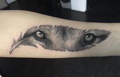 a black and white photo of a dog's eye tattoo on the left arm