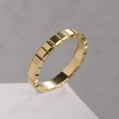 a gold wedding ring on top of a white surface