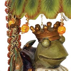 a frog with a crown on top of it's head sitting under a palm tree