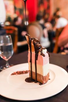 a piece of cake sitting on top of a white plate next to a glass of wine