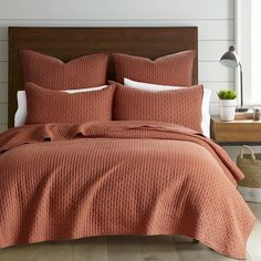 a bed with an orange bedspread and pillows