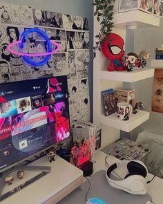 a desk with a monitor, keyboard and headphones on it in front of some books