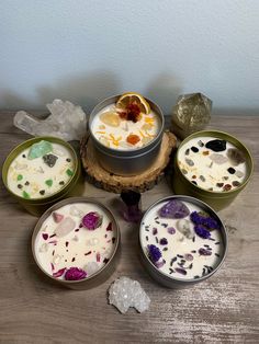 four bowls filled with different types of food on top of a wooden table next to crystals